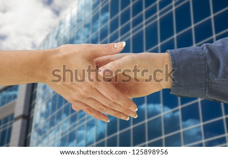 Man and Woman Shaking Hands In Front of Corporate Building Background.