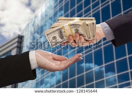 Male Hand Handing Stack of Cash to Woman with Corporate Building.
