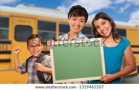 Young Mixed Race Students with Blank Chalkboard Near School Bus.