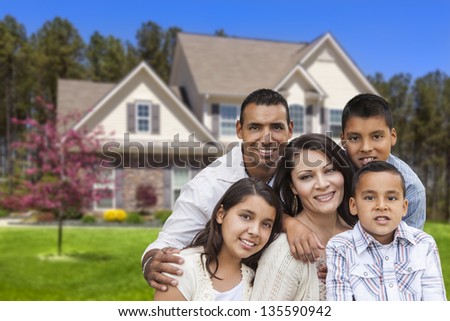 Happy Hispanic Family Portrait In Front Of Beautiful House.