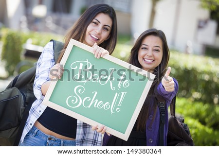 Excited Mixed Race Female Students Holding Chalkboard With Back To School Written on it.
