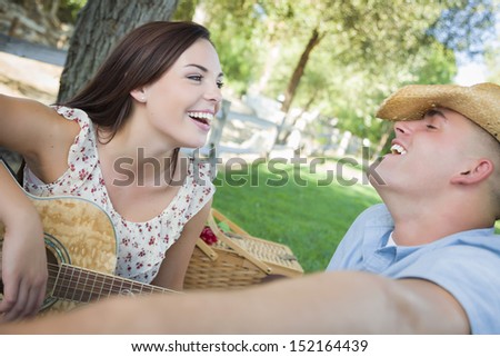 Happy Attractive Mixed Race Couple with Guitar and Cowboy Hat in the Park.