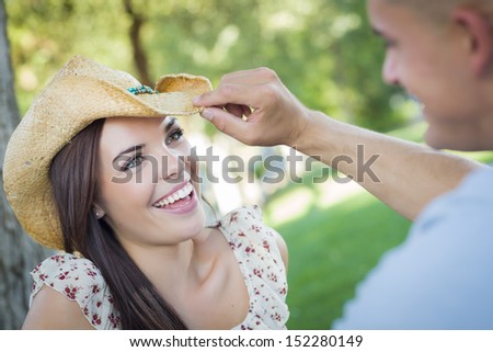Happy Mixed Race Romantic Couple with Cowboy Hat Flirting in the Park.