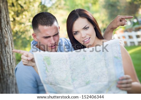 Lost and Confused Mixed Race Couple Looking Over A Map Outside Together.