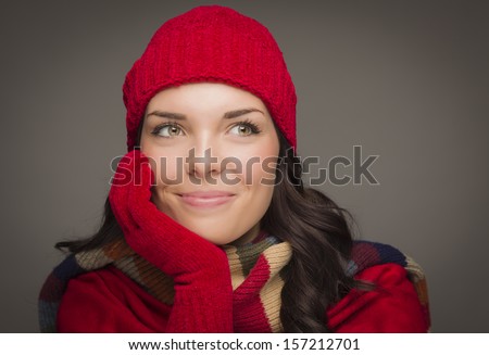 Happy Mixed Race Woman Wearing Winter Hat and Gloves Looking to the Side on Gray Background.