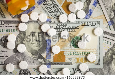 Medicine Pills Scattered on Newly Designed U.S. One Hundred Dollar Bills.