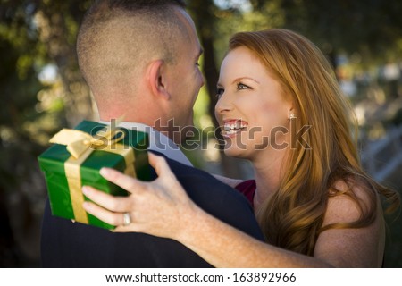 Smiling Beautiful Young Woman and Handsome Military Man Exchange a Christmas Gift.