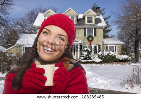 Happy Smiling Woman in Winter Clothing Holding Mug Outside of House in Snow.