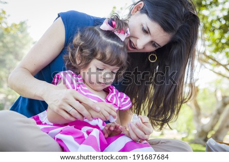 Mixed Race Young Mother and Cute Baby Girl Applying Fingernail Polish in the Park.