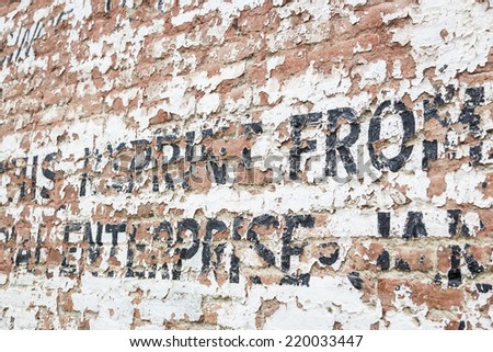 Old Weathered Brick Wall with Decaying Advertisement Writing.