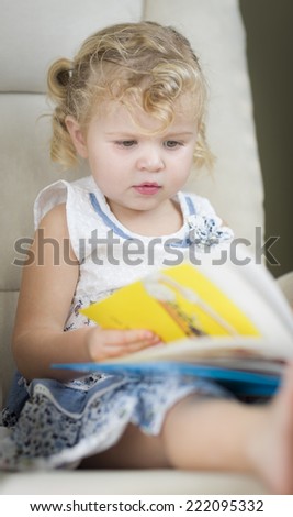 Adorable Blonde Haired Blue Eyed Little Girl Reading Her Book in the Chair.