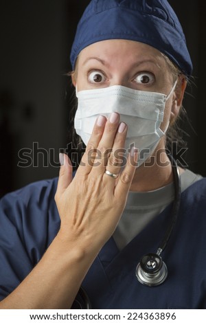 Shocked Looking Female Doctor or Nurse with Hand in Front of Mouth.