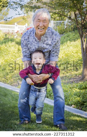 Happy Chinese Grandpa Having Fun with His Mixed Race Grandson Outside.
