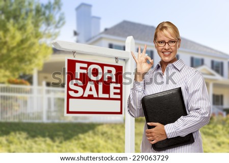Female Real Estate Agent in Front of Home For Sale Sign and House.