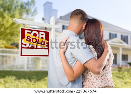 Sold For Sale Real Estate Sign and Affectionate Military Couple Looking at Nice New House.