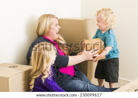 Playful Young Family In Empty Room Playing With Moving Boxes.