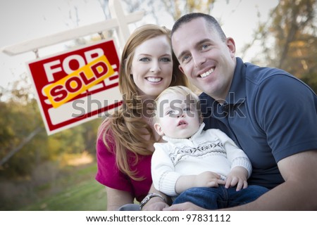 Happy Young Caucasian Family in Front of Sold Real Estate Sign.