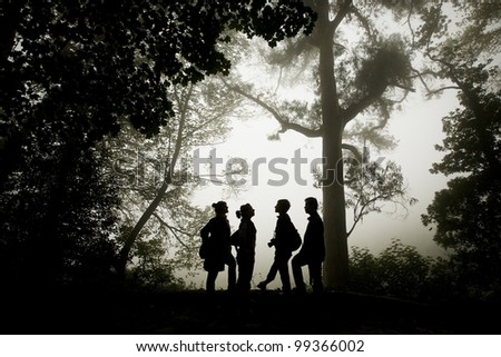 Group of people silhouette in the misty forest.
