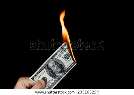 Human hand holding a burning 100 dollar bill