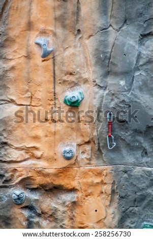 Multicolored climbing wall with support equipment on it.