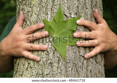 Earth Day Concept: Eco minded person hugging a tree with a green leaf between their hands.