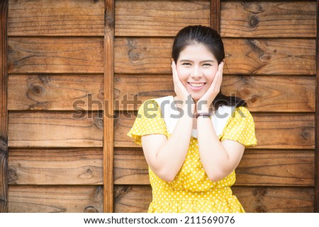 Happy Beautiful Woman Smiling wearing yellow shirt, Asian girl,Thai lady,wood background.Closeup portrait, winning, successful,Positive human emotion facial expressions