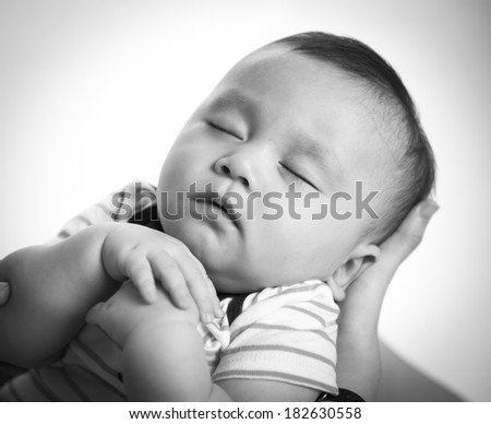close-up portrait of a beautiful sleeping baby in mom\'s hands