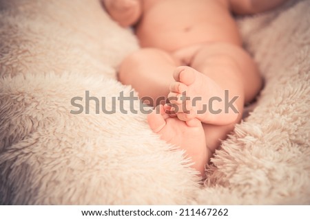 baby feet with toes curled up, on white fur background