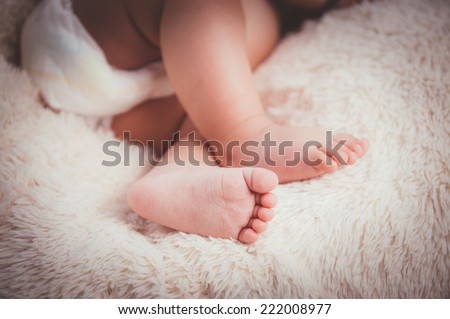 Little feet, focus on the right foot. Baby legs and bottom in diaper