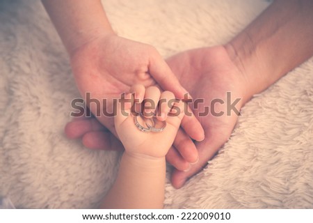 Baby hand. Closeup of baby hand into parents hands. Family concept with the wedding rings on baby hand.
