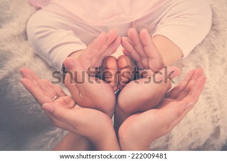 Newborn baby feet parents holding in hands. New born kind and Love symbol as heart sign. Vintage colour