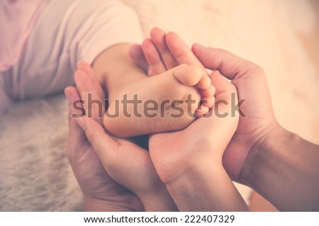 Closeup of baby feet into parents hands. Family concept Vintage colour