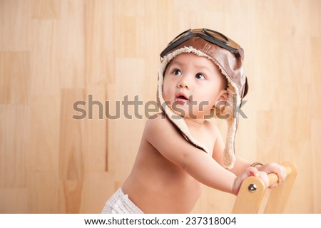 Image of one year old East Asian baby boy standing on wooden background, sweet little baby dreaming of being pilot
