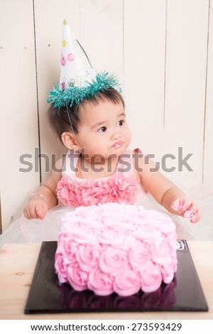 Surprised baby eating first birthday cake