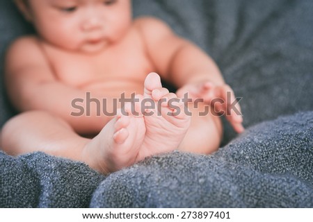 Funny chubby baby playing with its feet. Focus on feet
