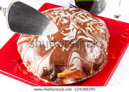 cake with glaze of chocolate in the red dish on the white table