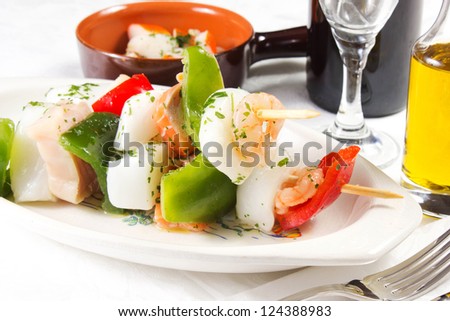 fish skewers  on a white table with oil and wine
