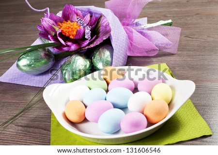 Colorful Easter Eggs with flowers and chocolate eggs on the table and white background