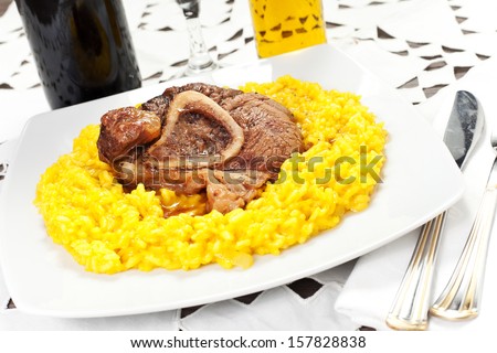 rice with saffron and bovine meat on the table with red wine and oil