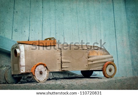 Old wooden rustic toy car on a light blue textured artistic background