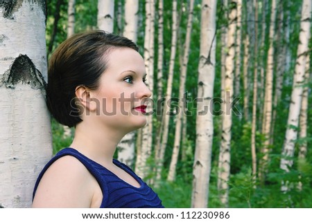 Attractive young woman (brunette) posing in a Scandinavian birch tree forest in summertime