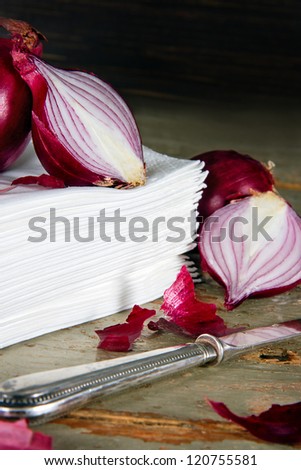 Red onions on a pile of paper tissues, vintage wooden dark background