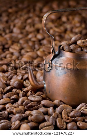 Old small rustic coffee pot with light roasted coffee beans