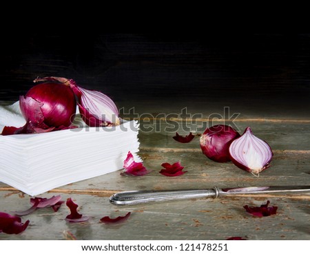 Red onions on a pile of tissues, rustic wooden background and copy text