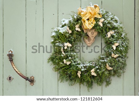 Green Christmas wreath with a golden bow on a wooden green rustic door