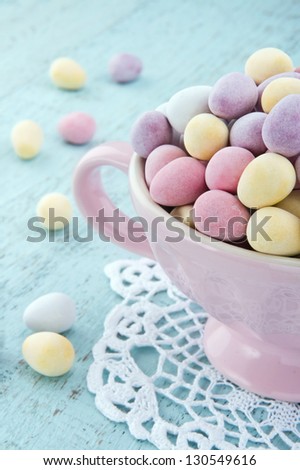 Small easter eggs in a pink cup on light blue wooden table
