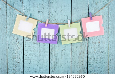 Four empty colorful photo frames or notes paper hanging with clothespins on wooden blue vintage shabby chic background