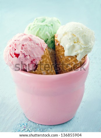Three ice cream cones in a pink jar on blue vintage wooden background