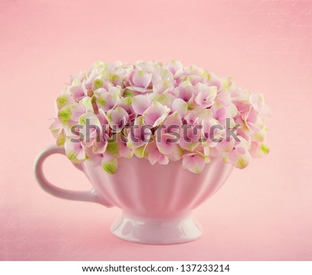Pink hydrangea flowers in a shabby chic mug on pastel vintage background with copy space
