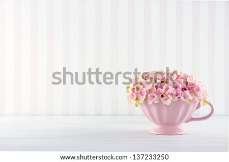 Pink hydrangea flowers in a shabby chic mug on vintage background with copy space